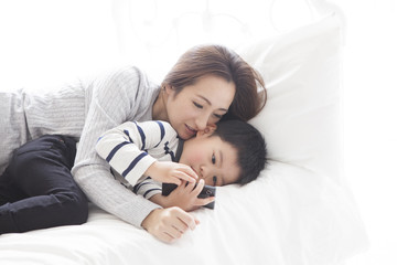 Mother and son are watching smartphone in bedroom