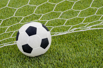 The soccer football with the net on the artificial green grass soccer field