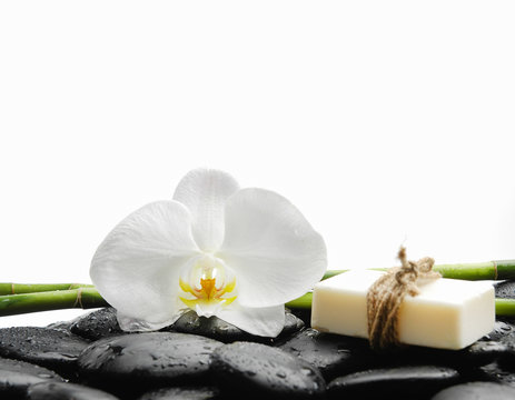 White orchid with black stones ,grove,soap on wet background
