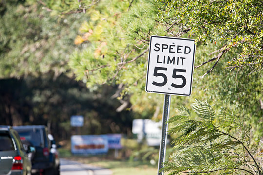 White sign with "speed limit 55" printed in black on country roa