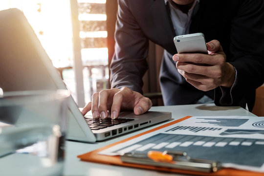 businessman working with digital tablet computer and smart phone with financial business strategy layer effect on desk in morning light
