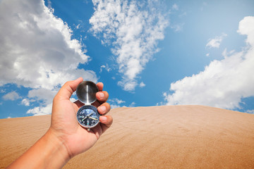 Hand holding compass in the desert.