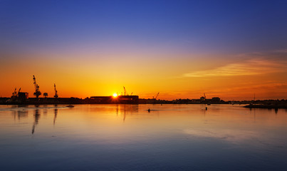 Piscataqua River, Portsmouth, New Hampshire with the sun rising behind the Navy Yard buildings in Kittery, Maine.