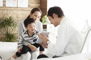 Obraz premium Pediatrician physician is showing tablet to mother and child