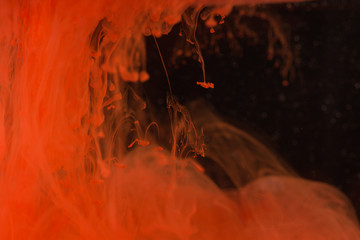 Red paint on the dark background doing stains because of drop into water. Looks like blood.