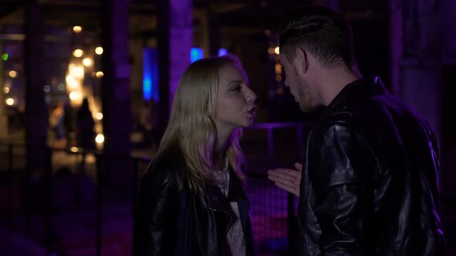 Jealous guy talking to girlfriend near night club, relationships, disagreement