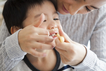 Mother is brushing her son's teeth