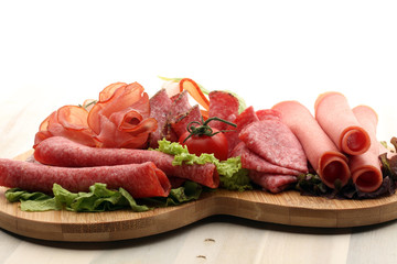 Food tray with delicious salami, pieces of sliced ham, sausage, tomatoes, salad and vegetable -...