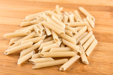 Brown rice penne isolated on a wood background