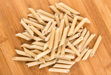 Brown rice penne isolated on a wood background