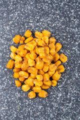 Roasted salted corn nuts on a mottled grey blue background