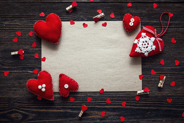 Blank sheet of brown paper with red hearts on old wooden table.