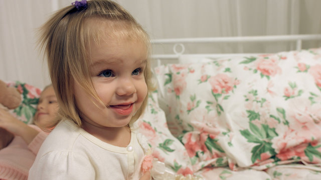 Adorable little girl sitting on a bed with her sister