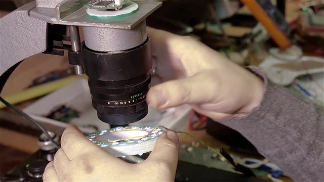 Engineer checking quality of repair of motherboard of smartphone iphone using handmade electron microscope