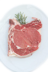 Bistecca di manzo con l'osso su piatto con rosmarino isolato su sfondo bianco