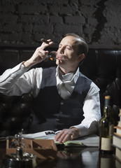 Man drinks alcohol and smokes a cigar