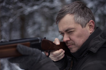  Hunter with a gun. Hunting in the winter forest.
