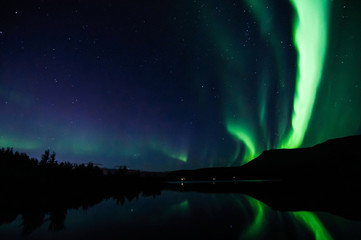 Northen lights (Aurora Borealis) in Iceland with mirroring on the lake