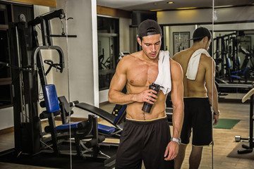 Muscular young man resting in gym during workout