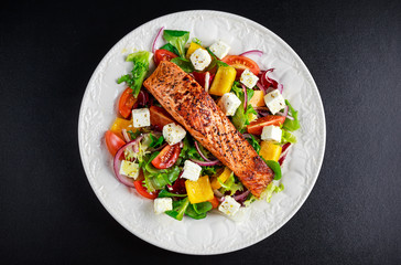 Fried Salmon steak with fresh vegetables salad, feta cheese. concept healthy food.