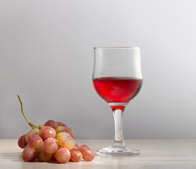 Виноградное вино в стеклянном бокале и гроздь винограда.\Полезное натуральное виноградное вино.