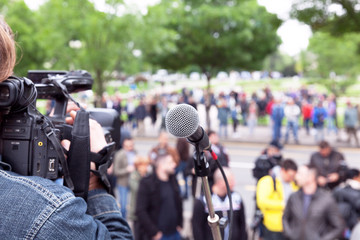 Microphone in focus, cameraman filming blurred crowd