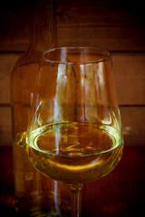 Glass of white wine with bottle in background. Selective focus
