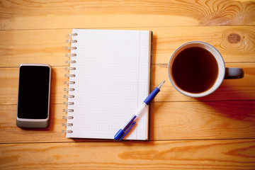 Notebook , tea cup and smart phone on wooden background