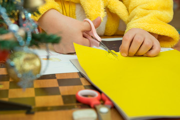 The child cuts out a star from construction paper, preparing a Christmas crafts, close-up