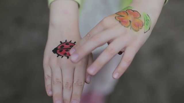 Hands of little girl with aqua makeup.
