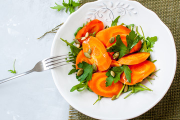 Simple salad of baked carrots with arugula and butter. Vegan healthy lunch or dinner.