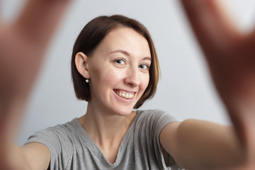  Smiling cheerful girl with freckles doing selfie. Stretching th