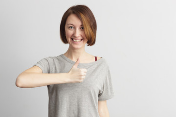 Red-haired girl with freckles showing a thumbs up, approving choice