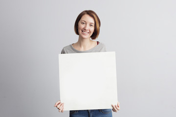 Beautiful caucasian girl holding a blank poster for text or ad.