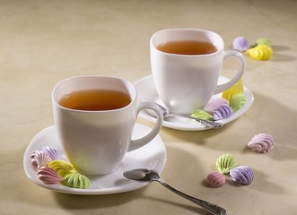 two white cups of tea with colorful meringue