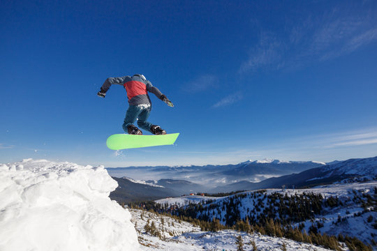 Jumping snowboarder in mountains in ski resort on blue sky background Dragobrat