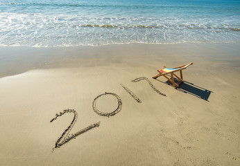 2017 written in sand write on tropical beach with Deck chair.