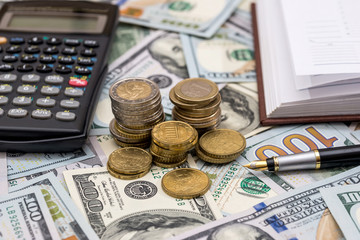 Fototapeta premium us coin on top dollar bills with pen and calculator.