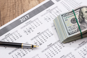 calendar with a pen and dollars.