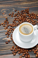 roasted coffee beans and cup on wooden background