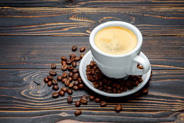 roasted coffee beans and cup on wooden background