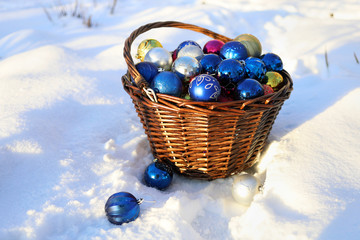 Christmas decorations in a wicker basket. Winter garden in the snow.
