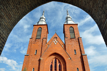 Fototapeta na wymiar The front facade of the Gothic church in the village Mstibovo of red brick, Grodno region, Belarus. View from the arch, look up.