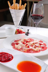 Fine dining - beef and parmesan carpaccio with red sauce and wine
