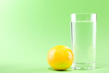 glass of water with lemon on a green background