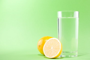 glass of water with lemon on a green background
