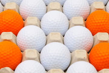 White and orange golf balls in the box
