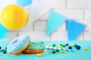 Two donuts and Birthday decor on blurred brick wall background