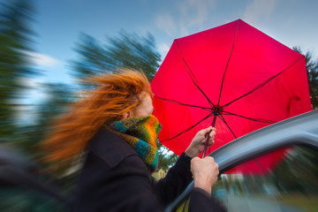 an einem stürmischen Tag versucht eine Frau einen Regenschirm aufzuspannen