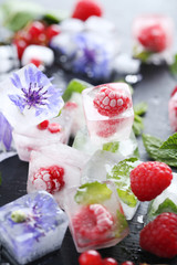 Fototapeta na wymiar Ice cubes with raspberries and mint leaf on wooden table